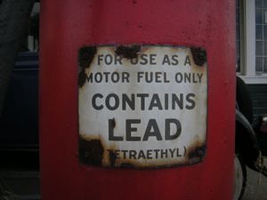 a closeup of a red gas pump with a warning label that reads, "for use as a motor fuel only" (بخط أكبر) "تحتوي رصاص" (وبخط أصغر) "(tetraethyl)"