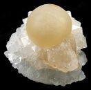 Translucent ball of botryoidal fluorite perched on a calcite crystal