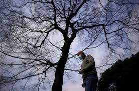 A man wearing a face mask jogs past a tree at a park in china.jpg