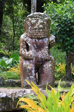 Photo d'une statue de tiki en pierre de deux mètres cinquante de haut. Le bras gauche est manquant.