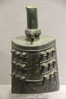 Bell with three rows of three knobs on each side, swirling decorative patterns and an inscription