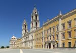 A massive building with yellow facade and two bell towers in the middle