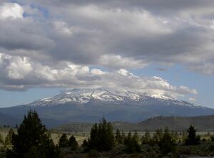 Mount Shata on a partly or mostly cloudy day, with the base forested and snow and rock higher up
