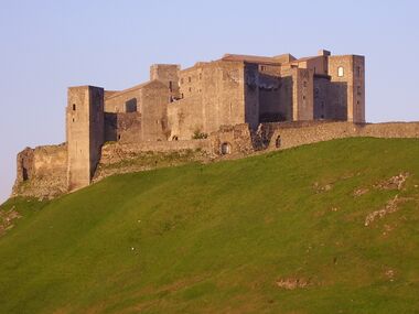 Castle against sky, with sloping grass in front