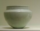 A blue-grey bowl with a nearly perfect half sphere body, and a rim that narrows from the edge of the half sphere, then goes up slightly.