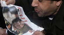 متظاهر يبصق على صورة معمر القذافي 20 فبراير 2011.