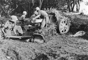German soldiers in uniform with helmets, serving as crew of an anti-tank gun