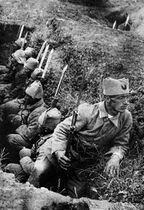 Soldiers in a trench, with one looking in a different direction