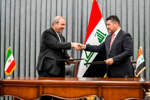 رئيس ديوان رئيس الوزراء إحسان العوضي (يمين) وسفير إيران لدى بغداد محمد كاظم الصادق في أثناء تبادل التوقيع على اتفاق لمقايضة النفط .png