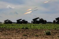 آليات عسكرية تطلق صواريخ في أحد الحقول.